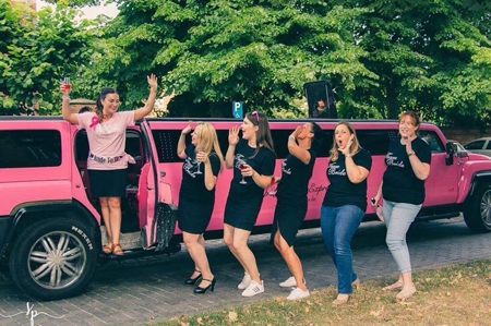 Meisjes bij de roze Hummer limousine tijdens een vrijgezellenfeestje